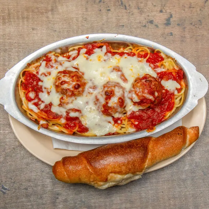 Baked spaghetti and meatballs with melted mozzarella and a garlic roll